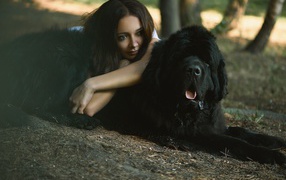 Девушка лежит на большой черной собаке