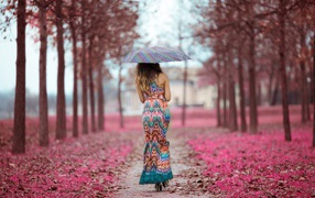 Девушка под зонтом в красивом платье идет по аллее