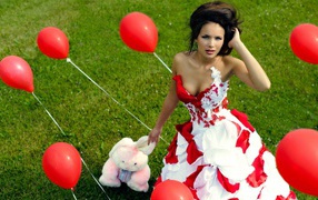 Девушка с игрушкой среди красных воздушных шариков