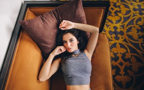 Модель Aurela Skandaj лежит на диване