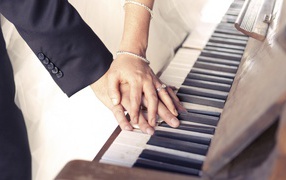 Hands of lovers on the piano