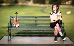 Скрипачка читает книгу и посматривает на скрипку