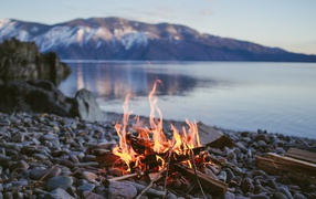 Bonfire on the pebbles on the shore of the lake