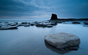 Плоские камни в серой воде у берега