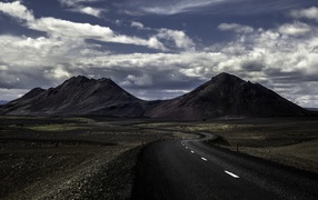 The road goes across the plain to the mountains
