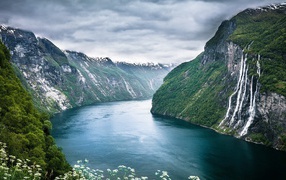 Water flows from a cliff into the fjord