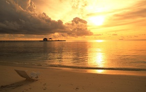 Одинокий шезлонг на пляже на закате