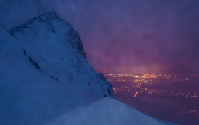 Заснеженная скала на фоне ночного города