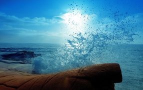 Голубая волна разбилась о камень на берегу