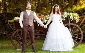 Жених и невеста на фоне телеги цветов
