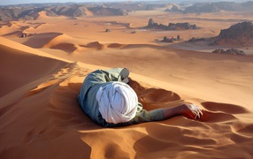 Человек лежит на песке в пустыне