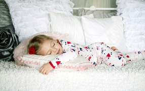 Девочка в пижаме спит на кровати