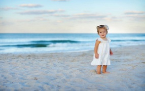 Девочка в белом платье на песке пляжа