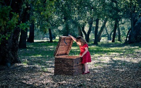 Девочка заглядывает в плетеную корзину