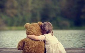 Девочка сидит в обнимку с плюшевым медведем