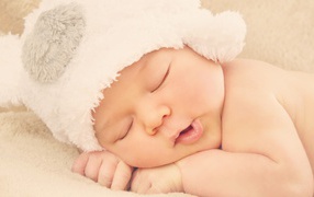 Спящий ребенок в белой шапке