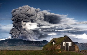 House in Iceland erupting volcano on the background