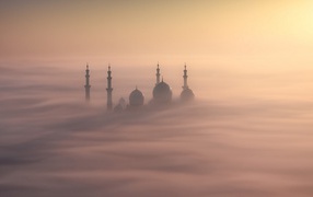 The minarets of the mosque look out from the fog