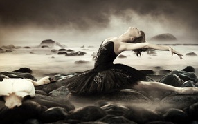 Ballerina in black dress among the waves