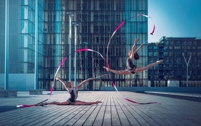 The gymnasts with ribbons in the square in front of a skyscraper