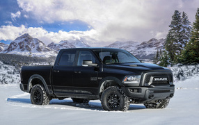 The car is a pick-up truck Ram 1500 Rebel Black, 2017 on a background of snow-capped mountains