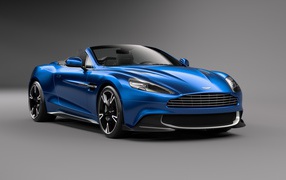 Синий кабриолет  Aston Martin Vanquish S Volante на сером фоне 