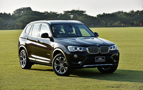 Черный автомобиль  BMW X3 на поле для гольфа 