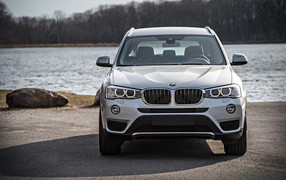 Серебристый автомобиль BMW X3 у водоема 