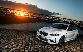 Белый автомобиль BMW M2 на фоне заката 