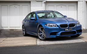 Синий автомобиль BMW 5 Series у гаража