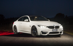 Белый автомобиль BMW M4 Coupe Pure Edition с включенными фарами