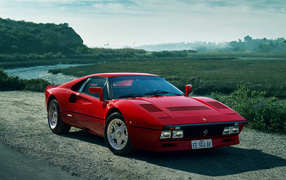 Красный быстрый автомобиль Ferrari 288 GTO у реки