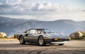 Суперкар Ferrari 308 gts серого цвета,   на фоне гор 