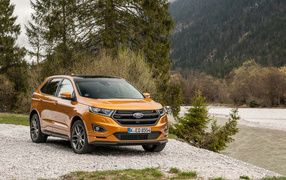 Оранжевый внедорожник Ford Edge на фоне деревьев