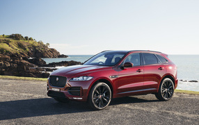 Бордовый автомобиль Jaguar F-Pace на фоне океана