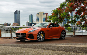 Оранжевый автомобиль Jaguar F-Type на фоне небоскребов 