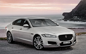 Silver car Jaguar XF on the background of the ocean