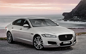 Серебристый автомобиль Jaguar XF на фоне океана
