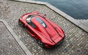 Красный спортивный автомобиль Koenigsegg Regera у воды, вид сверху