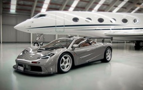 Спортивный автомобиль McLaren F1 на фоне самолета