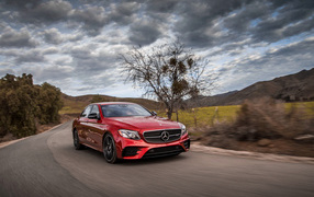 Стильный красный автомобиль Mercedes-Benz E-Class на фоне неба 