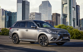 Серебристый автомобиль Mitsubishi Outlander на фоне небоскребов 