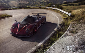 Быстрый бордовый автомобиль Pagani Zonda на крутом повороте