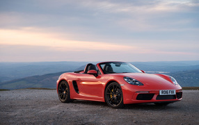 Красный автомобиль кабриолет Porsche 718 Boxster на фоне горизонта 