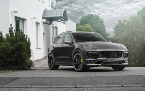Серебристый автомобиль Porsche Cayenne стоит у дома