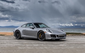 Silver car Porsche 911 Carrera 4 GTS Coupe in the background of a stormy sky