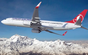 Boeing 737 - 900ER Turkish Airlines airline flies over the snow-capped mountains