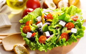 Аппетитный Греческий салат на тарелке с листьями салата