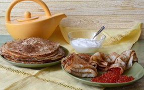 Appetizing pancakes with sour cream and red caviar on the table