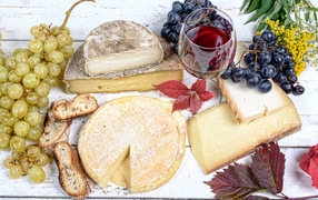 Дорогой сыр с плесенью на столе с виноградом и красным вином